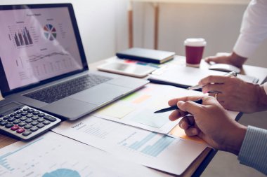 Ofis odasındaki bütçe toplantısında finansal planlama grafiği ve şirket bütçesini tartışan iki iş ortağı analiz stratejisi.