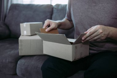 Asyalı girişimci ergen müşterinin sipariş ettiği ürünü kutuya koymak için bir karton kutu açıyor..