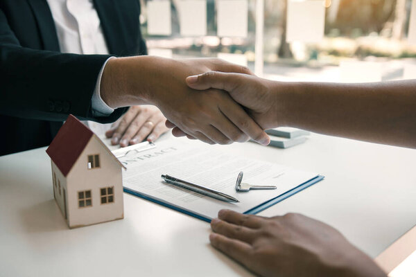 Торговые агенты и покупатели дома работают над подписанием новых домов и рукопожатием.
