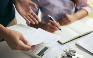 İki Asyalı çift ve erkek ve kadın birlikte tasarruf ekonomisi kavramına sahip mevduat hesapları ve günlük gelir kaynaklarının giderlerini veya finansmanlarını analiz ediyorlar.