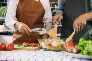 Asyalı çift mutfakta sağlıklı salata hazırlıyor..