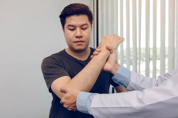 亚洲理疗师检查接受骨科康复的病人的肘部 — 图库照片