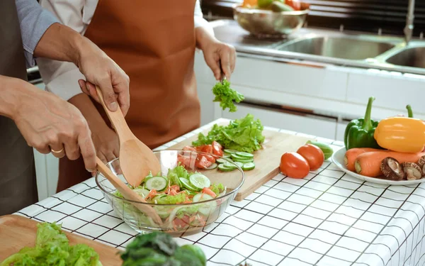 Asyalı çift mutfakta sebze salatası pişiriyor..