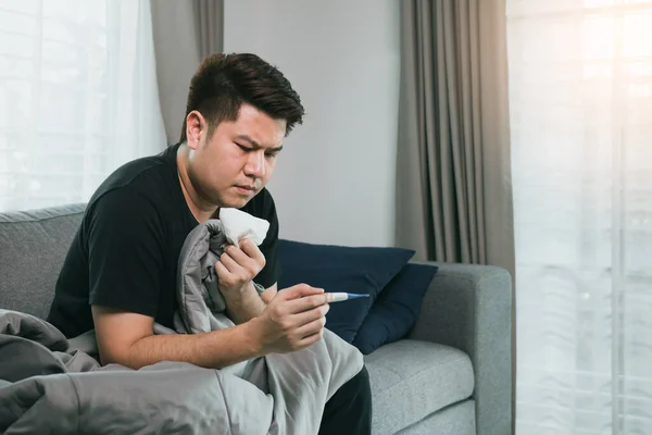亚洲人感到压力很大 因为他咳嗽 并使用温度计检查家里是否发烧或生病 — 图库照片
