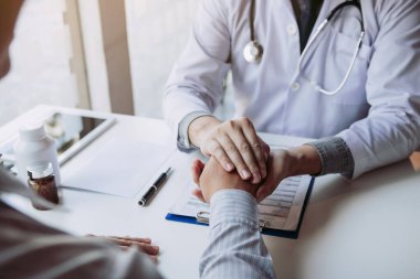 Doktor hastanın elini tutuyor ve hastalığın semptomlarını tedavi etmek için umut veriyor..