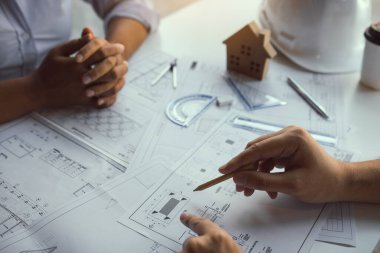 Ortaklık mühendisi ya da iş arkadaşı bir proje üzerinde çalışıyor ve plan belgelerine bakmakla birlikte tartışıyorlar..