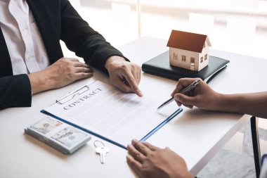 Emlakçı, ajans ofisindeki müşteriye ev modelini vererek yeni alıcıyı tebrik ediyor..