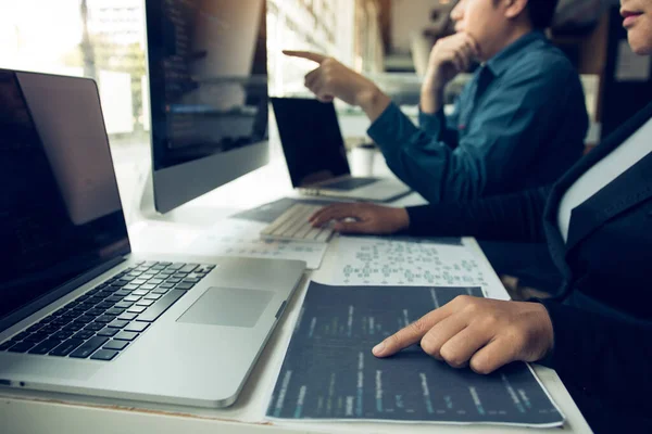 İki yazılım geliştiricisi bilgisayardaki programa yazılan kodu birlikte analiz ediyor..