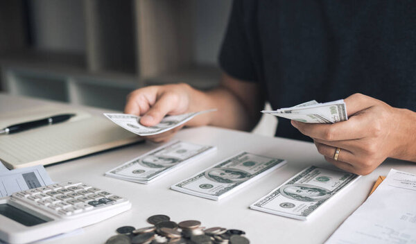 Азиатские мужчины держат банкноты наличными и выкладывают их на стол с идеей экономии денег.