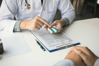 Doktor, ofisteki tümörlerin tedavisi için ilaç kullanımına ilişkin tavsiyelerde bulunmak üzere bir ilaç paneli tutuyor..