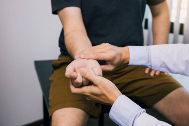 Fizyoterapist, klinikte bilek kemiğine bastırarak hastanın bileğini kontrol ediyor..