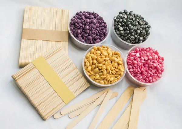 beyaz bir arka plan üzerinde kavanoz farklı renkler ve değnek Depilasyon için toz sıcak balmumu ile vardır.