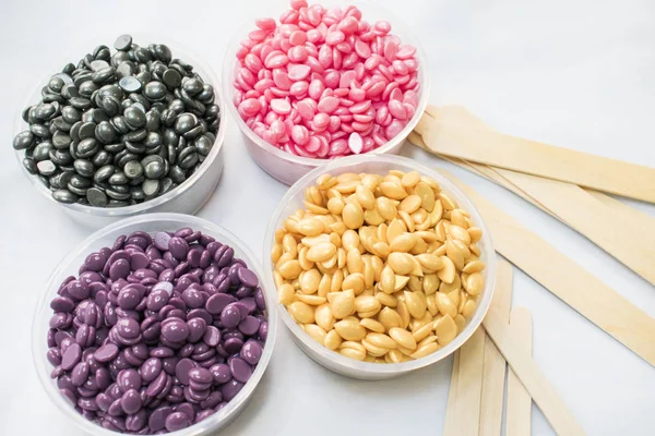 beyaz bir arka plan üzerinde kavanoz farklı renkler ve değnek Depilasyon için toz sıcak balmumu ile vardır.