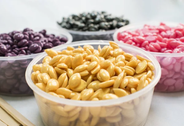 beyaz bir arka plan üzerinde kavanoz farklı renkler ve değnek Depilasyon için toz sıcak balmumu ile vardır.