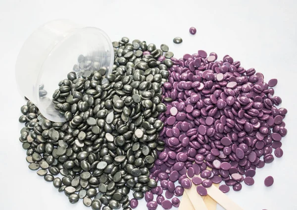 beyaz bir arka plan üzerinde boşaltma granüller vardır ve gümüş cila ve ahşap Depilasyon için sopa.