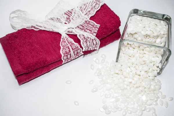 Beyaz arka plan üzerinde izole beyaz toz mum ve bir yay ile kırmızı bir havlu var.