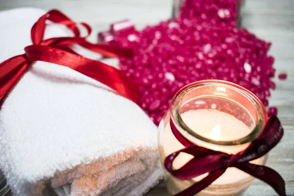yanan bir mum ve bir beyaz havlu, kırmızı toz balmumu arka planı yakındır.