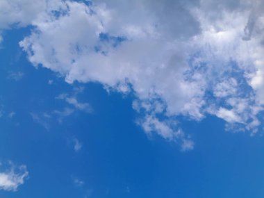 Arkaplanda mavi gökyüzü manzaralı bulutlar var. Mavi gökyüzünde güzel güneşli bulutlar. Güneş kabarık bulutların arasında parlıyor.