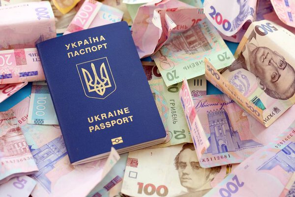 Украинский биометрический паспорт лежит на большом количестве различных украинских гривен денежных счетов крупным планом