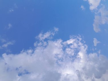 Arkaplanda mavi gökyüzü manzaralı bulutlar var. Mavi gökyüzünde güzel güneşli bulutlar. Güneş kabarık bulutların arasında parlıyor.