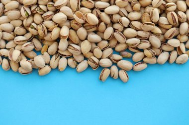 Parlak mavi arkaplanda soyulmamış fıstıklar, üst görünüm düz arkaplan deseni ve kopyalama alanı