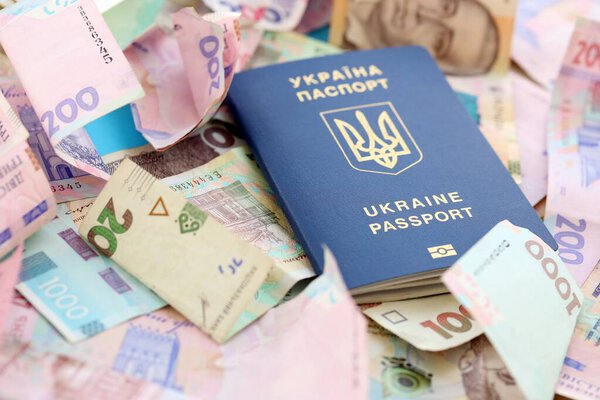 Украинский биометрический паспорт лежит на большом количестве различных украинских гривен денежных счетов крупным планом