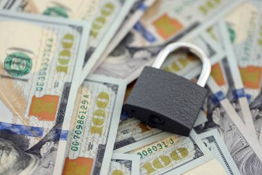 Küçük siyah asma kilit, büyük miktarlarda yeni yüz dolarlık banknotların üzerinde yatıyor.