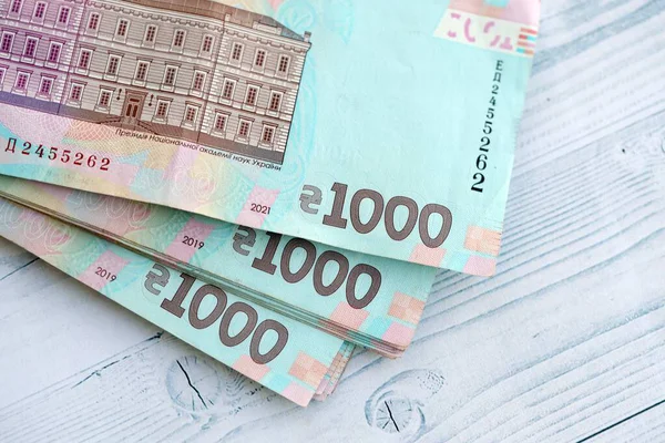 Beyaz ahşap masa üzerinde modern tasarımı olan büyük miktarda Ukrayna yapımı 100 Hryvnia para faturası. Finansal konsept, iş ücretleri