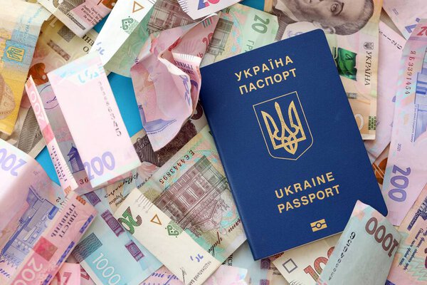 Украинский биометрический паспорт лежит на большом количестве различных украинских гривен денежных счетов крупным планом