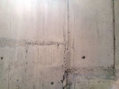 Koyu su ve yağ izlerinin olduğu gri beton duvarın dokusu dikey olarak aşağı iniyor ve birçok iz ve çizgi grundge