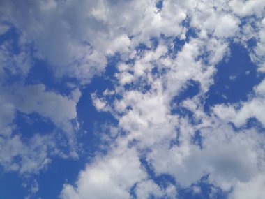 Arkaplanda mavi gökyüzü manzaralı bulutlar var. Mavi gökyüzünde güzel güneşli bulutlar. Güneş kabarık bulutların arasında parlıyor.