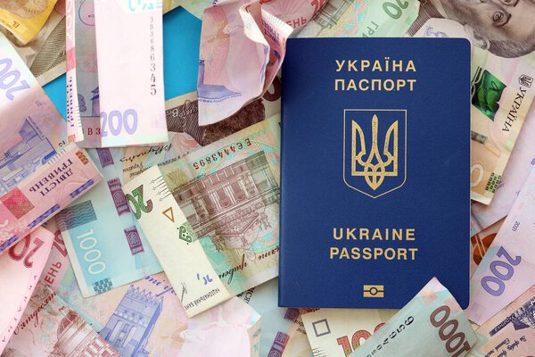 Украинский биометрический паспорт лежит на большом количестве различных украинских гривен денежных счетов крупным планом