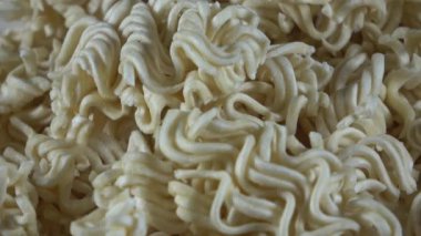 Ezilmiş kurutulmuş ramen eriştesi parçaları dönen videoyu kapatıyor.