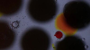 Yağ ve su kabarcıkları, siyah noktaların üzerinde yavaşça ilerler ve mürekkep lekeleri ayrışır.