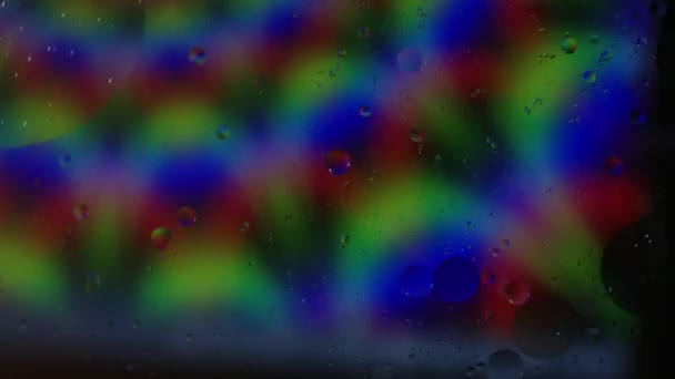 油と水の泡はサイケデリックなレーザー渦巻きパターンの上でゆっくりと動く — ストック動画