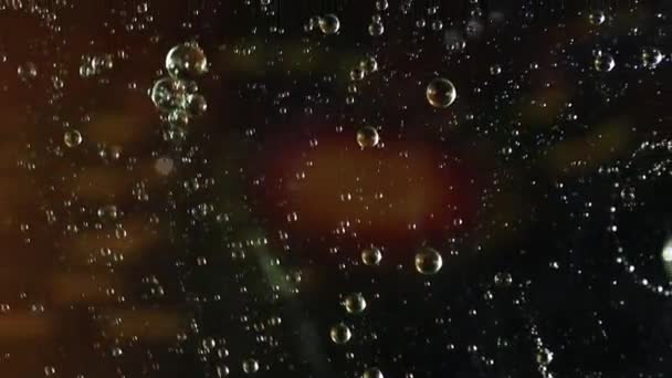 油と水の泡が赤と黒の背景の上に渦巻く — ストック動画