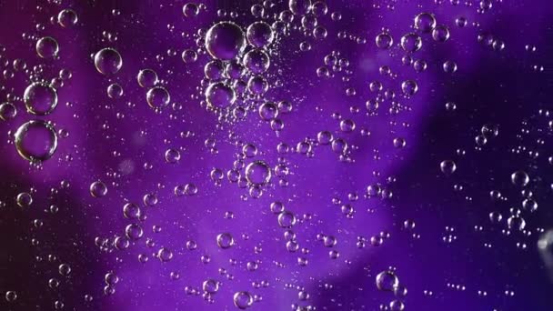 油と水の泡は 紫と青の神秘的な空間の背景の上にゆっくりと渦巻く — ストック動画