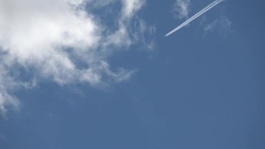 Bulutlu mavi gökyüzü boyunca uzanan jet parkurları