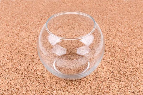 Clear glass bowl on a plain cork board background