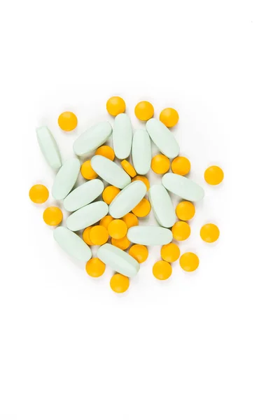 白い背景の上に散らばった緑と黄色の錠剤 — ストック写真