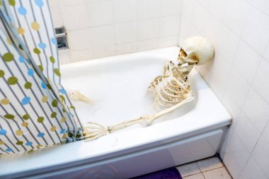 Kemikli iskelet bir grungy off-beyaz kirli küvet bir kabarcık banyo alarak