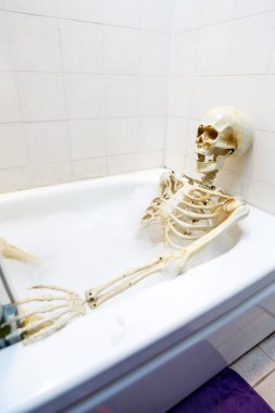 Kemikli iskelet bir grungy off-beyaz kirli küvet bir kabarcık banyo alarak