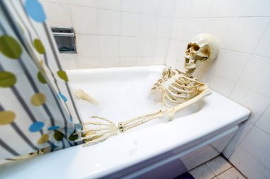 Kemikli iskelet bir grungy off-beyaz kirli küvet bir kabarcık banyo alarak