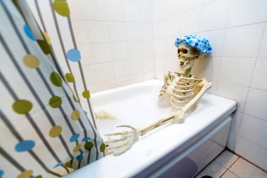 Kemikli iskelet bir grungy off-beyaz kirli küvet bir kabarcık banyo alarak