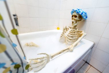 Kemikli iskelet bir grungy off-beyaz kirli küvet bir kabarcık banyo alarak