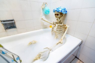 Kemikli iskelet bir grungy off-beyaz kirli küvet bir kabarcık banyo alarak