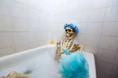 Kemikli iskelet bir grungy off-beyaz kirli küvet bir kabarcık banyo alarak