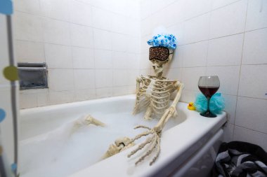 Kemikli iskelet bir grungy off-beyaz kirli küvet bir kabarcık banyo alarak