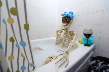 Kemikli iskelet bir grungy off-beyaz kirli küvet bir kabarcık banyo alarak