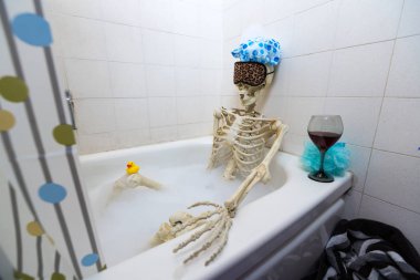 Kemikli iskelet bir grungy off-beyaz kirli küvet bir kabarcık banyo alarak